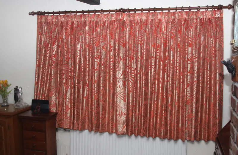 Coral pencil pleat curtains in a bedroom by Heather Horrocks Leigh