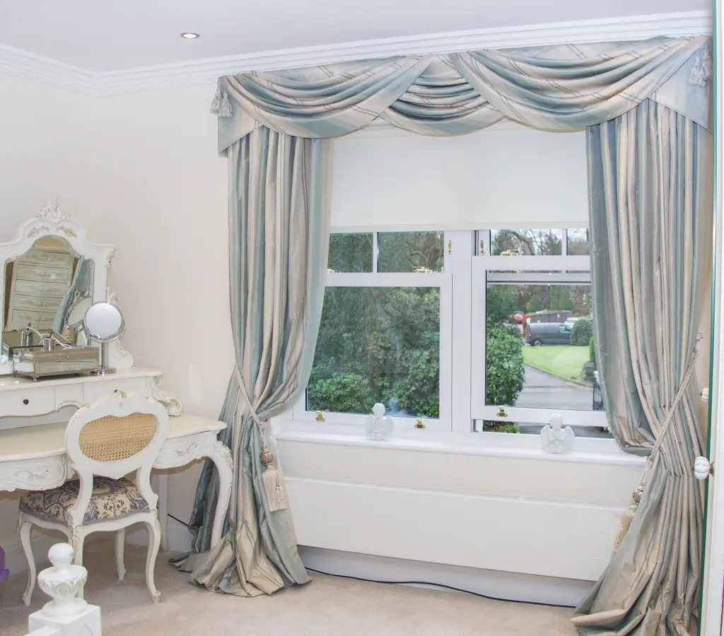 Silver swags and tails with curtains in a bedroom by Heather Horrocks Leigh