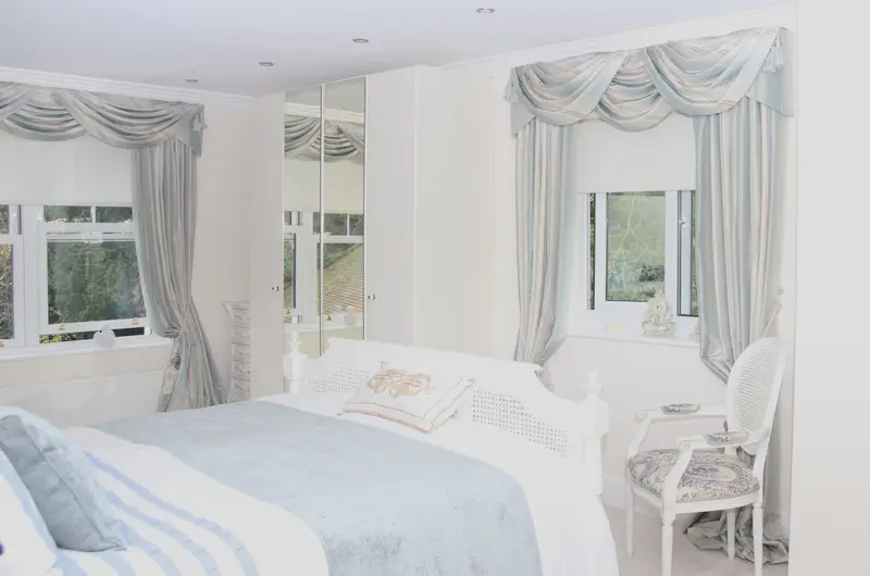 Swags and tails window treatment in a white bedroom by Heather Horrocks Leigh