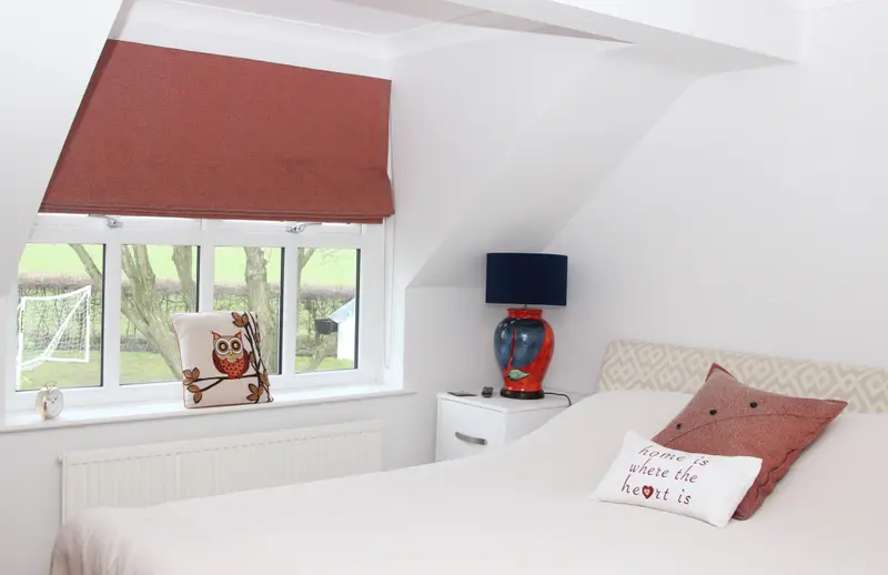 Terracotta Roman blind in a bedroom by Heather Horrocks Leigh